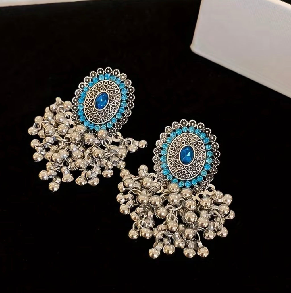 Bohemian-style oxidized silver dangle earrings featuring blue rhinestone centers and beaded tassels