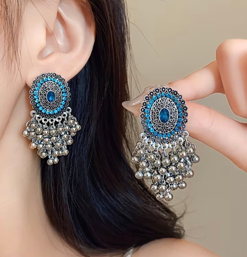 Bohemian-style oxidized silver dangle earrings featuring blue rhinestone centers and beaded tassels