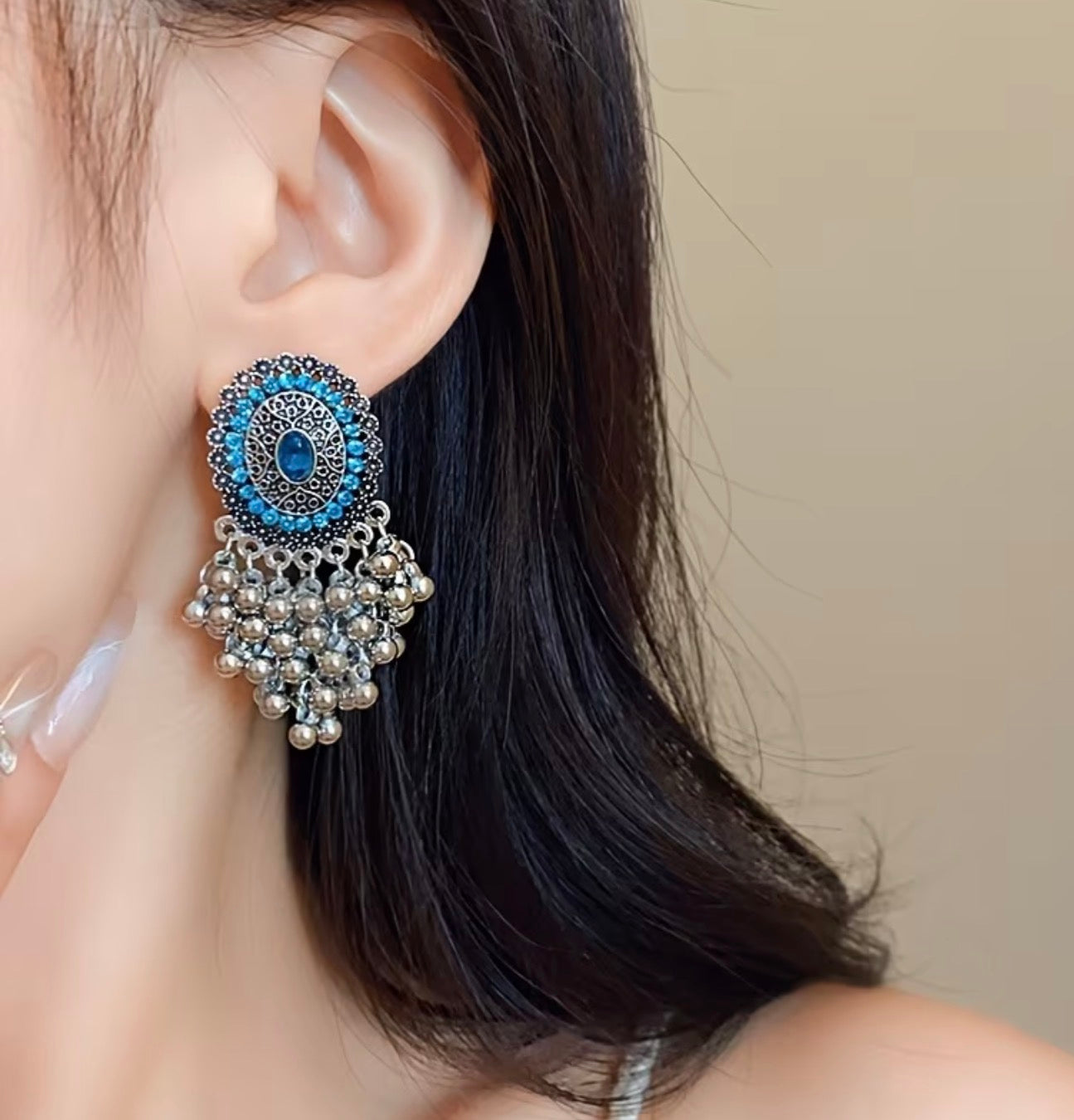 Bohemian-style oxidized silver dangle earrings featuring blue rhinestone centers and beaded tassels